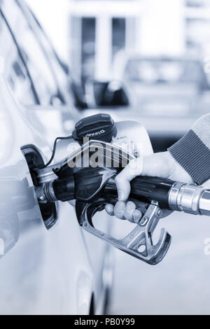 Primo piano della mano mans pompando benzina in auto alla stazione di gas. Foto Stock