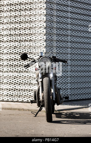 Custom Moto parcheggio vicino alla parete del palazzo delle finanze. Tutto è pronto per divertirsi dopo la dura giornata in ufficio. Moderno e giovane imprenditore hipster Foto Stock