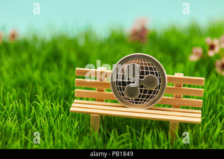 Ripple moneta sul banco in erba di un giardino come un capitolo impianto. Concetto Foto Stock