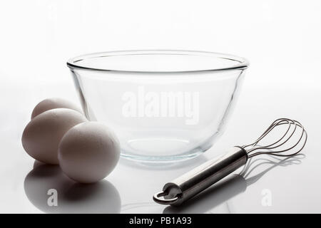 Trasparente come il vetro ciotola con baffo di metallo e tre le uova bianche a prescindere dal lato Foto Stock