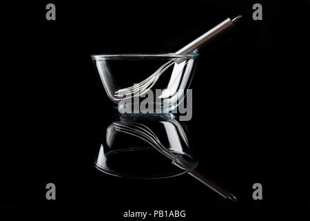 Trasparente come il vetro ciotola con baffo di metallo interno su sfondo nero in vista laterale con la riflessione Foto Stock