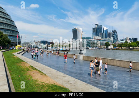 La folla sulla riva sud del fiume Tamigi vicino al City Hall, Londra UK, in estate, guardando ad ovest verso la città Foto Stock