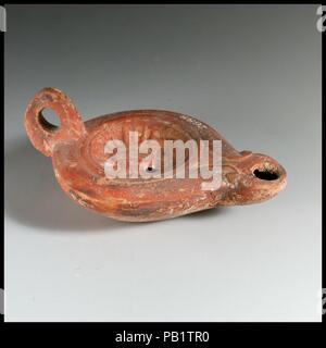 Olio di terracotta con lampada. Cultura: romana, cipriota. Dimensioni: complessivo: 1 3/4 x 4 1/8 in. (4,5 x 10,5 cm). Data: ca. A.D. 75-125. Loeschcke Tipo 4. Stampo-realizzato, con anello di maniglia. Discus: irradiare testa di Helios (Sol), affacciato e lunari crescent sotto; un unico foro di riempimento in basso a sinistra e una fascia comprendente una singola linea a rilievo affiancato da due scanalature intorno discus; semplice, leggermente inclinato spalla, terminanti in volute semplificata ad ugello. Incisa anello di base e irregolare, base cava. Intatto. Museo: Metropolitan Museum of Art di New York, Stati Uniti d'America. Foto Stock