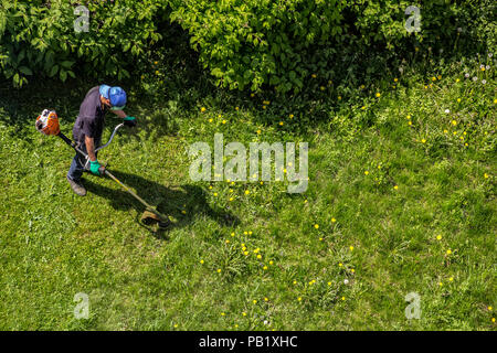 Lavoratore di sesso maschile con potenza stringa attrezzo tagliaerba tosaerba per taglio di erba, vista dall'alto Foto Stock