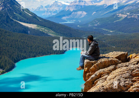 Un escursionista seduta sul bordo del Vertice di prua guardando il Lago Peyto nel Parco Nazionale di Banff sulla Icefields Parkway. Il ghiacciaio-lago alimentato è famosa per l'it Foto Stock