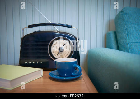 Una radio e una tazza di tè accanto a un lettino di teal Foto Stock