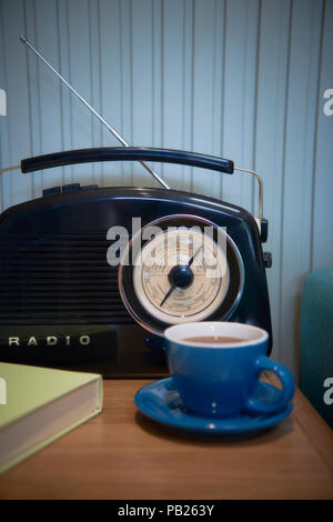 Una radio e una tazza di tè accanto a un lettino di teal Foto Stock