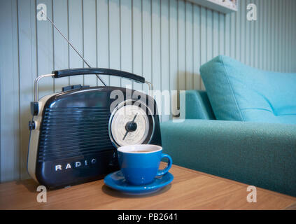 Una radio e una tazza di tè accanto a un lettino di teal Foto Stock