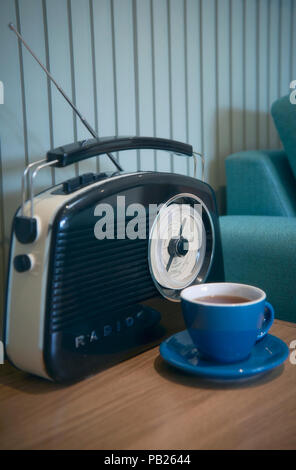 Una radio e una tazza di tè accanto a un lettino di teal Foto Stock