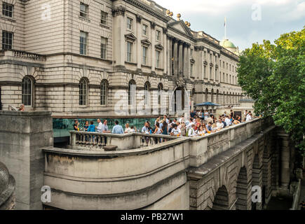 Una funzione con persone che si rilassano e hanno un drink sulla terrazza affollata fuori Somerset House, un edificio classificato di grado 1 a Londra, Inghilterra, Regno Unito. Foto Stock