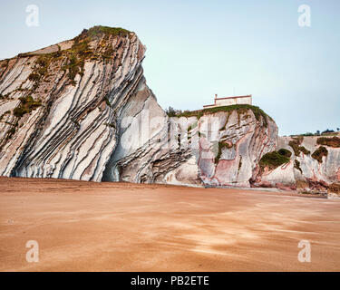 Le scogliere di flysch nel parco geologico a Spiaggia di Itzurun, con la Cappella di San Telmo sulla rupe, Zumaia, Paesi Baschi, Spagna. Foto Stock