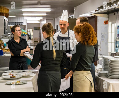 Cucina dell'Hotel Lenkerhof, Lenk, Svizzera. Stefan Lünse, il capo chef del Lenkerhof, spiega al personale del servizio ogni sera prima di cena quali piatti sono disponibili per la selezione nel ristorante gourmet Spettacolo Foto Stock