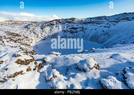 Vista panoramica del Vulcano Kerid con neve e ghiaccio nel cratere vulcanico lago in inverno sotto un cielo blu chiaro. Situato nella zona Grímsnes in così Foto Stock