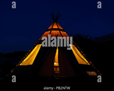 L' immagine di un teepee tende Tepee preso in serata, illuminato con luci interne Foto Stock