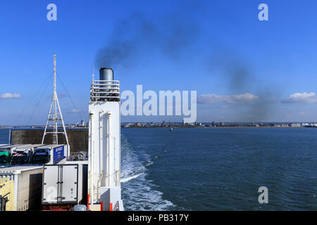 Fumo nero che esce da un imbuto di traghetto inquinando l'atmosfera contro un cielo blu Foto Stock