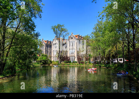 Barche a remi sul lago del Parco Dom Carlos 1 con gli edifici abbandonati dei padiglioni in background. Costruito nel 1893 dall'architetto Rodrigo Berq Foto Stock