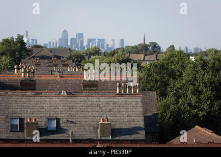 I tetti delle case di Sydenham e nella distanza, gli alti edifici di Docklands di Londra, il 23 luglio 2018, a Londra, in Inghilterra. Foto Stock