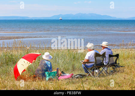 Troon, Ayrshire. Il 26 luglio 2018. Regno Unito: Meteo molti usufruire dell'insolitamente caldo e prendere per la spiaggia a raffreddarsi, prendere il sole o fare una nuotata in mare. Alan Clark, Heather Clark e Helen Feasey da Lanark percorsa a Troon spiaggia e ha trovato un posto abbastanza per un picnic Credito: Findlay/Alamy Live News Foto Stock