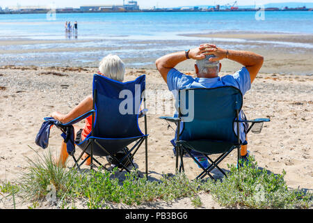 Troon, Ayrshire. Il 26 luglio 2018. Regno Unito: Meteo molti usufruire dell'insolitamente caldo e prendere per la spiaggia a raffreddarsi, prendere il sole o fare una nuotata in mare. Robert e Maureen Ballantyne da Glasgow Godetevi tutto un posto sulla spiaggia e a fare un po' di credito per prendere il sole: Findlay/Alamy Live News Foto Stock