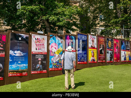 Edinburgh Food Festival 2018 in George Square Gardens, Edimburgo, Scozia, Regno Unito. Ci sono bancarelle prodotti alimentari con oltre 20 cibo e bevande locali produttori nella libera manifestazione all'aperto. Un uomo che indossa un cappello di Panama guarda al Edinburgh Fringe Festival manifesti in George Square che includono Andrew Lawrence, al di fuori del blu cantanti, Simon Evans e la Melomaniacs Foto Stock