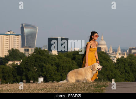 Londra, Regno Unito. 26 Luglio, 2018. Una giovane donna cammina con il suo cane a Londra, in Gran Bretagna il 26 luglio 2018. Le temperature nei prossimi giorni potrebbero rompere tutti a tempo di record del Regno Unito, con il mercurio dilagano a 37 gradi Celsius, è previsto il giovedì. Credito: Han Yan/Xinhua/Alamy Live News Foto Stock