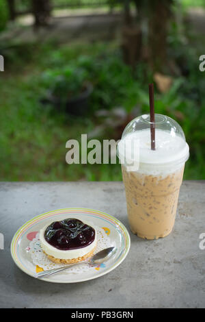 Caffè ghiacciato take away e una fetta di torta sul tavolo di calcestruzzo Foto Stock