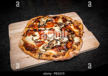 Fatte a mano in casa a fungo e il chorizo pizza appena sfornato sul pannello di legno Foto Stock