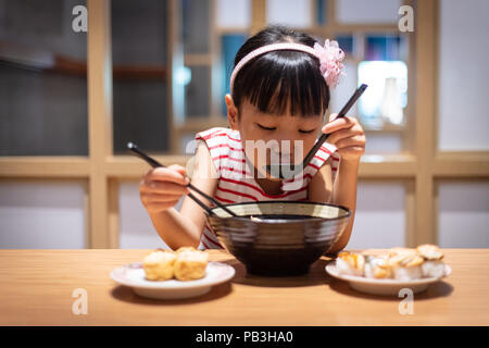 Asian poco ragazza cinese di mangiare spaghetti ramen presso un ristorante giapponese Foto Stock