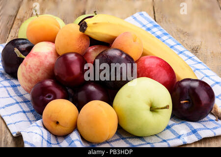 Frutta su un panno da cucina, mele, susine, albicocche e banana Foto Stock