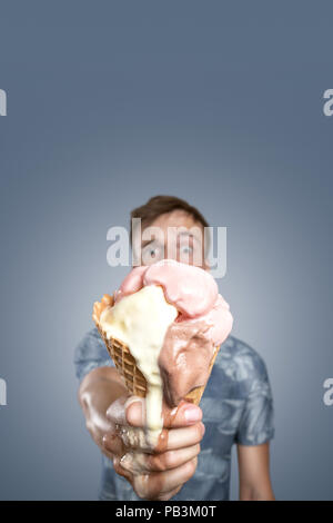 Uomo con un punto di fusione di cono gelato in mano Foto Stock