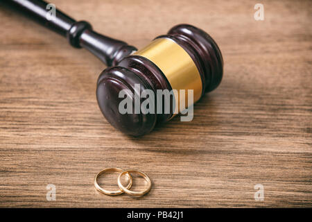 Concetto di divorzio. Gli anelli di nozze e giudice martello su sfondo di legno, spazio di copia Foto Stock