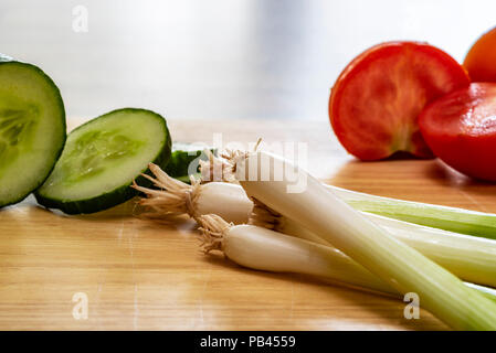 Cetriolo affettato , pomodoro e la molla onoins, ,su una cucina tagliere. Insalata di alcuni ingredienti. Foto Stock