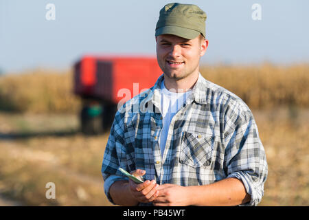 Felice giovane agricoltore dopo il raccolto di mais Foto Stock