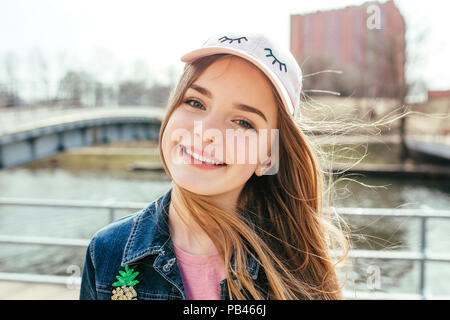 Ritratto closeup giovane e bella ragazza in città. Ragazza sorridente in hat Foto Stock