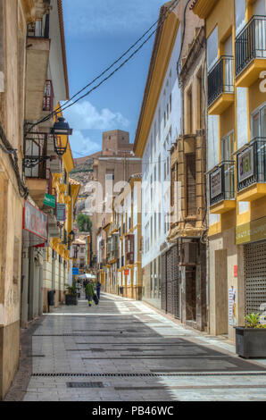 HDR di una stretta strada di Lorca con il castello di Lorca nella distanza, Murcia, Spagna Foto Stock