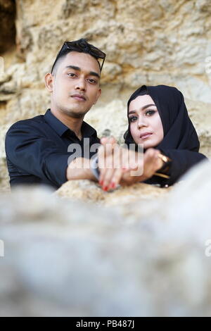 Coppia musulmana tenendo in mano la montagna roccia con abito nero Foto Stock