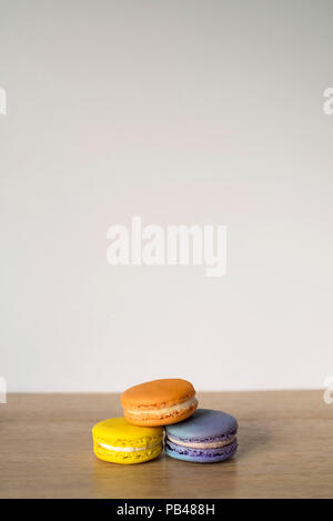 Trio di Macarons seduto su un banco di legno pronto a mangiare Foto Stock