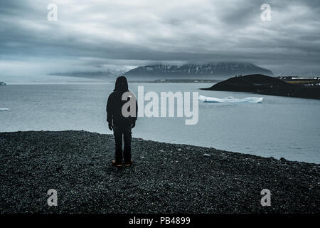 Giovane uomo jokursarlon affacciato sulla laguna glaciale in una nebbiosa giornata nel sud dell'Islanda Foto Stock