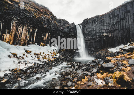 Drammatica vista la mattina del famoso Svartifoss (nero caduta) cascata. Estate colorato sunrise in Skaftafell, Vatnajokull National Park, l'Islanda, l'Europa. Stile artistico post elaborati foto. Foto Stock