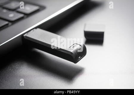 Macro di un Nero memory stick USB inserito nella porta USB di un computer portatile di colore nero, vista laterale Foto Stock
