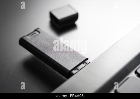 Primo piano di un Nero memory stick USB inserito nella porta USB di un Notebook nero, vista laterale Foto Stock