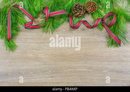 Due pigne lungo con il rosso e il verde Natale nastro bianco su rami di pino con spazio di copia Foto Stock