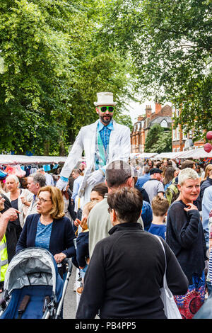 Uomo in un abito bianco su palafitte al "fair in piazza", un festival annuale di stagno quadrato e Sud Grove, Highgate Village, London, Regno Unito Foto Stock