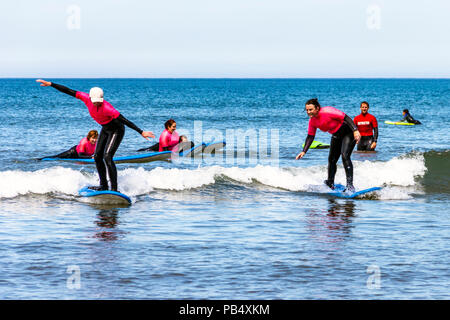 Un gruppo femminile di surfers prendendo lezioni in mare a Condino, Devon, Regno Unito Foto Stock