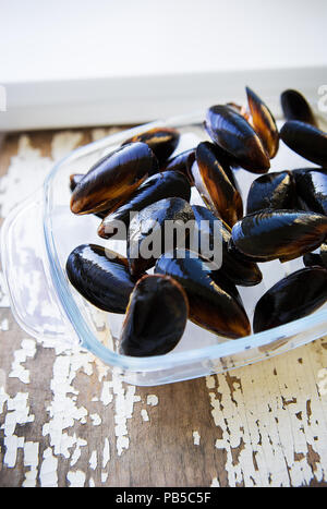 Cozze fresche su un vecchio legno tavolo bianco. Foto Stock