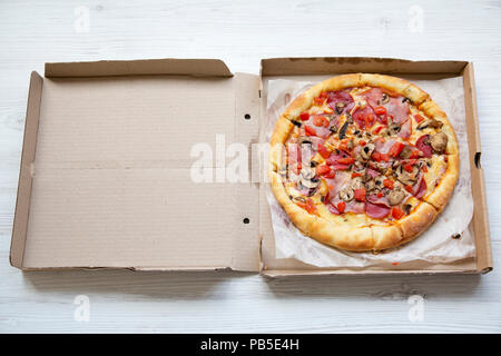 Pizza Fresca in una scatola di cartone bianco su una superficie di legno, angolo di alta. Vista dall'alto. Foto Stock