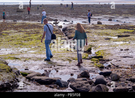 Persone Beachcombing ed esplorando Robin cappe baia vicino a Whitby North Yorkshire quando la marea è fuori Foto Stock