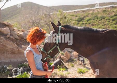 Bella capelli rossi alternativa femmina hanno cura di un cavallo bellissimo pronto a guidare e viaggiare insieme e scoprire luoghi sorprendenti. amicizia e t di origine animale Foto Stock