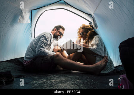 Felice giovane età media giovane sposato e in rapporto godetevi il campeggio all'interno della tenda e utilizzare internet tablet tecnologia. amore e amicizia fo Foto Stock