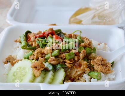 Agitare piccante pollo fritto con foglia di basilico sul riso nella casella di schiuma per portare a casa Foto Stock